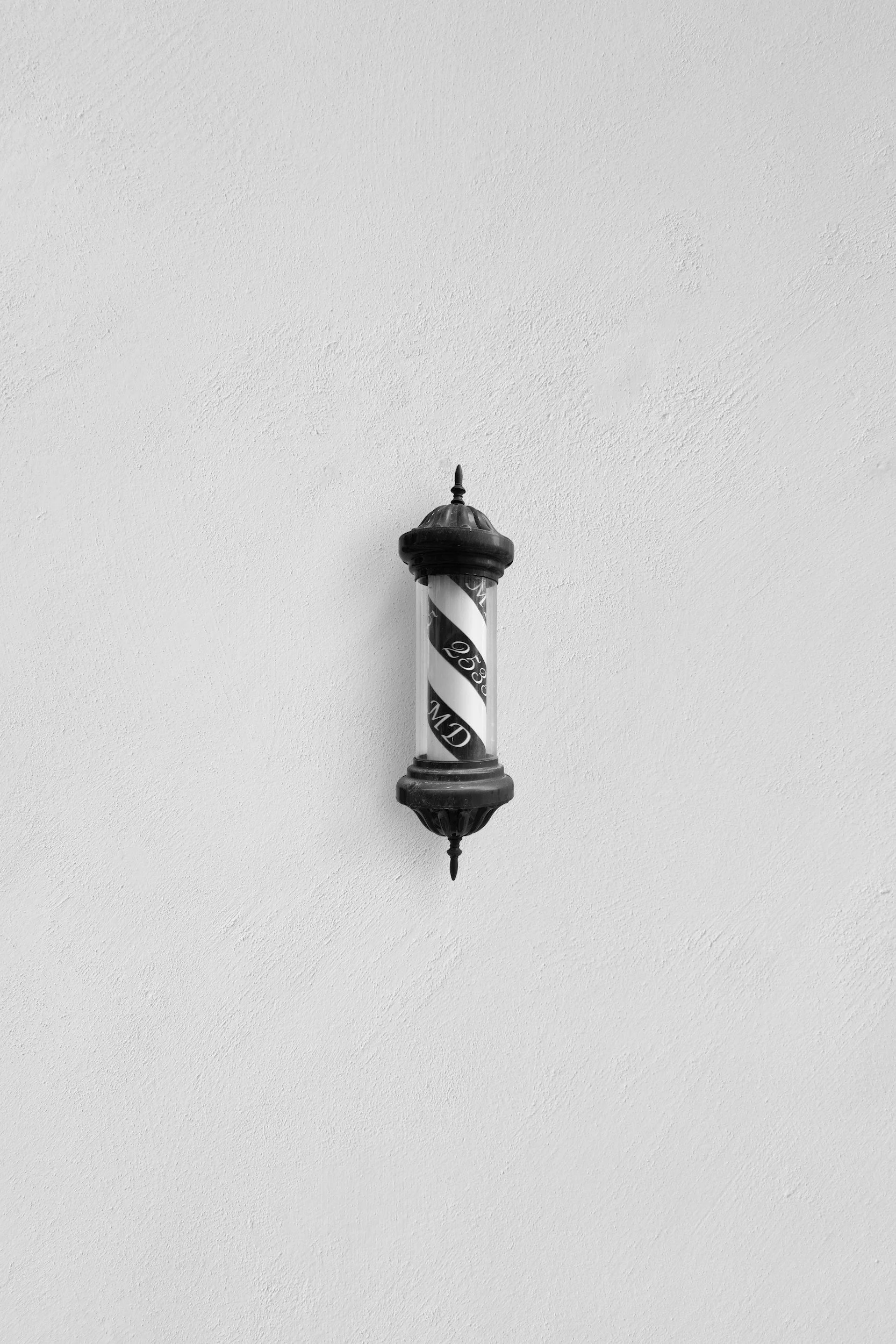 A black vintage street lamp mounted on a plain white wall.