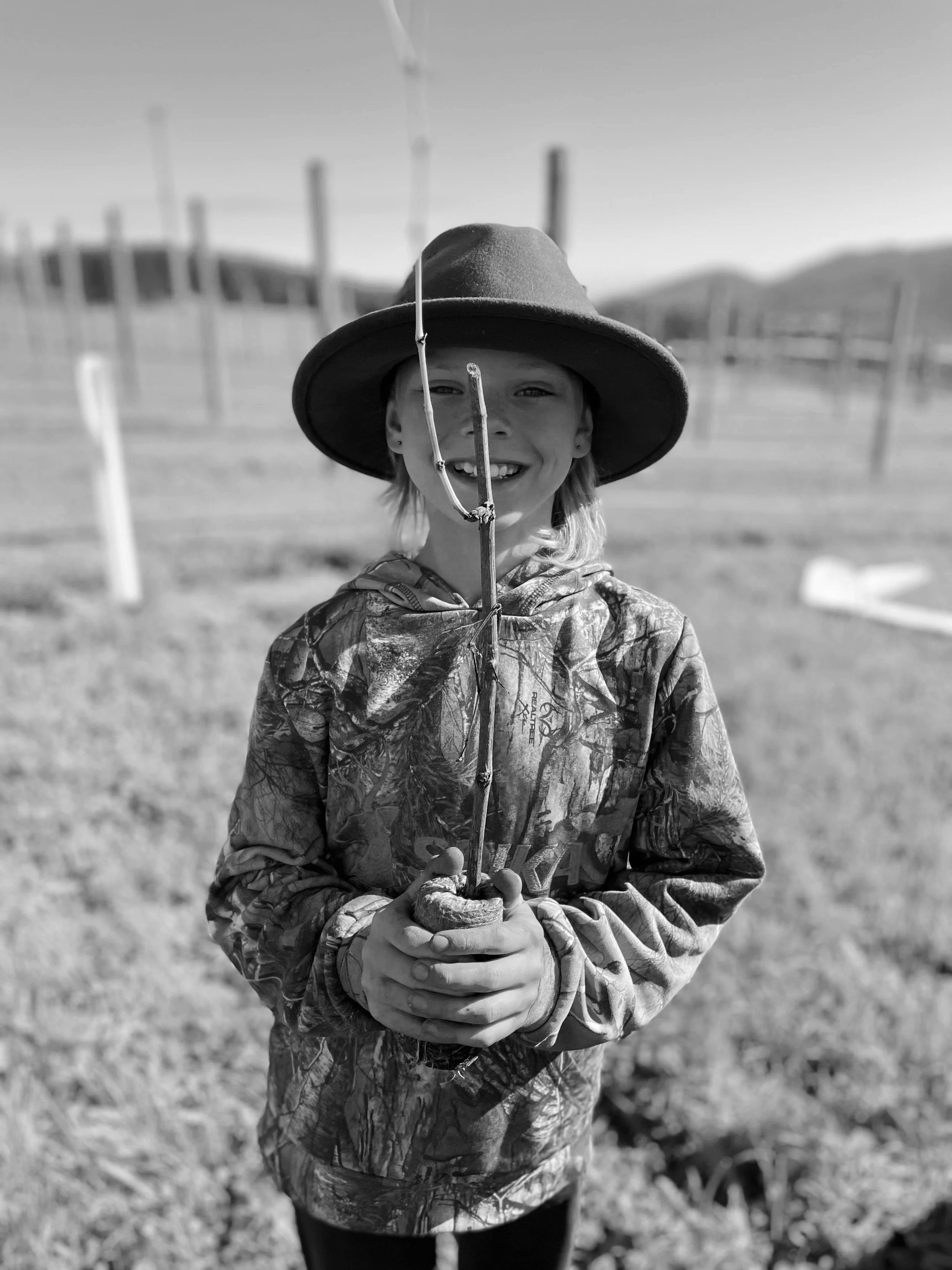 A smiling young person wearing a wide-brimmed hat and camouflage jacket, at Ten Mile Track in Scottsdale Tasmania.
