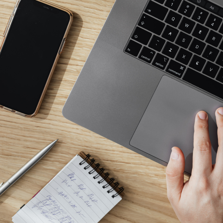 man working on his desk with his phone, notepad and pen to begin a marketing strategy