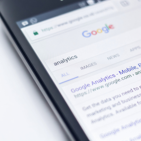 Image of a phone with a google search newsfeed for "analytics"