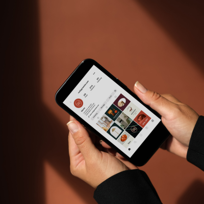 Person holding a smartphone displaying a gallery of images or videos.