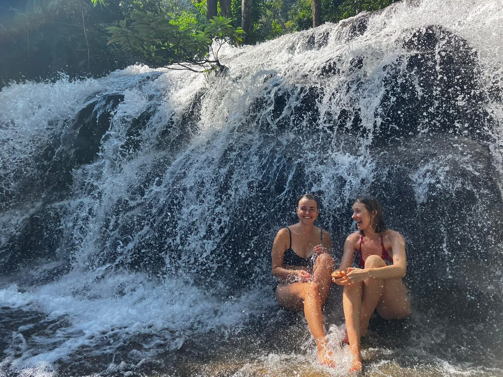 Ein Wasserfall im Doi Inthanon Nationalpark im Norden Thailands indem 2 Frauen baden gehen um sich nach der Wanderung abzukühlen.