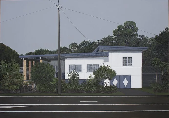 A modern white house with a blue roof and accents, surrounded by greenery, with a street and utility pole in the foreground.