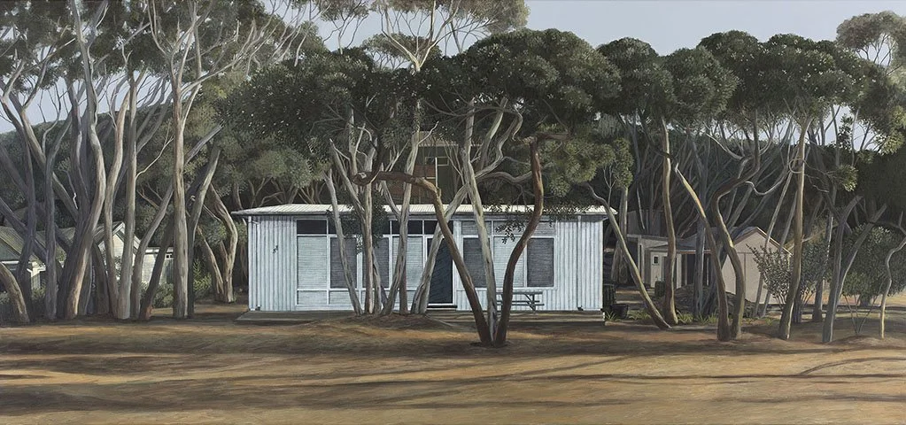 A small, white, rectangular cabin with metal siding sits among tall, twisted trees with thick trunks. The cabin has two windows, one of which is open, and there's a picnic table outside. The ground is mostly dirt with some shaded patches cast by the 
