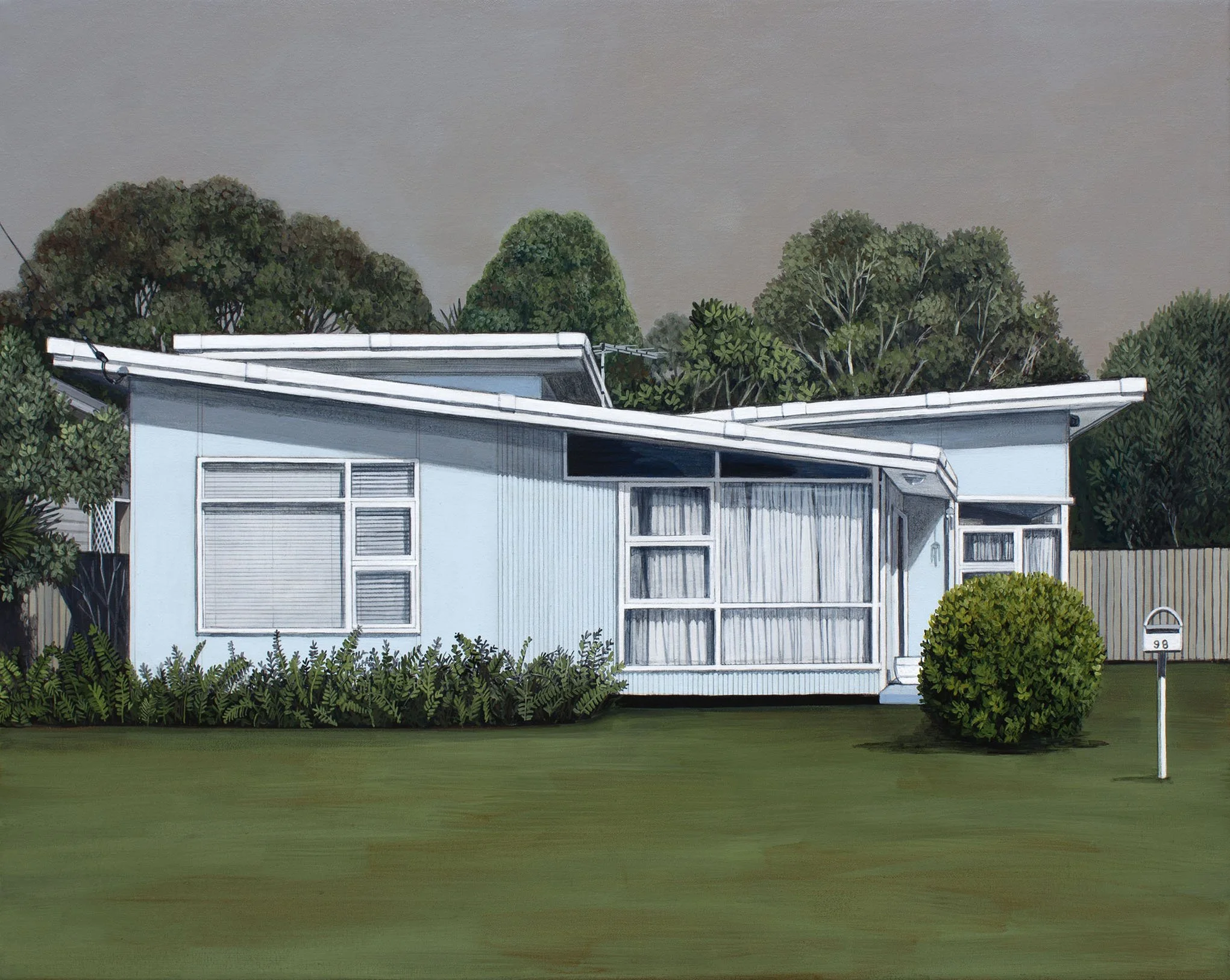 A modern house with large windows and a flat, overhanging roof, surrounded by green trees and shrubs, with a manicured lawn and a mailbox in the front yard.