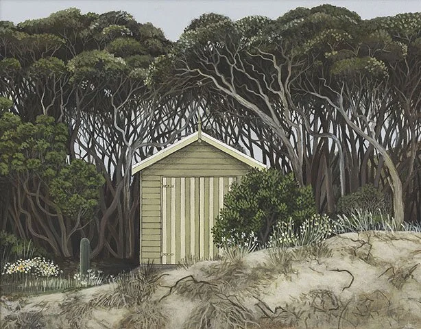 A small, light green shed with vertical wood paneling situated in front of a dense forest of dark, twisted trees with green foliage. The ground around the shed is sandy and features patches of grass and small plants.