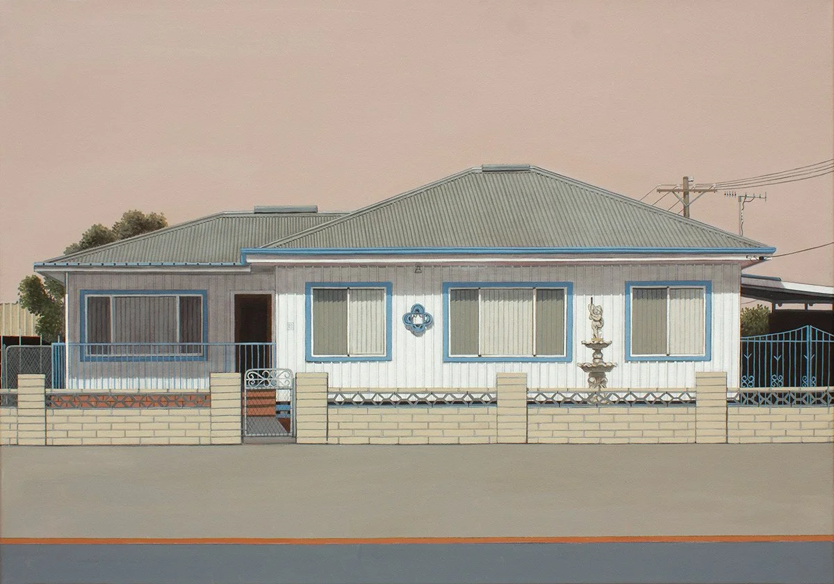 Front view of a house with a metal roof, white siding with blue trim, and a small front yard enclosed by a brick and metal fence.