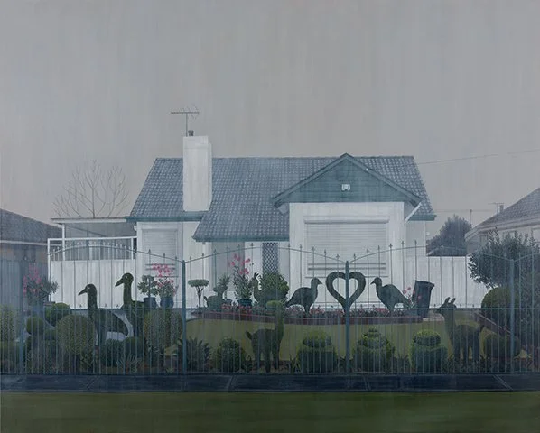 View of a backyard with a decorative fence featuring swan and heart shapes, surrounding various potted plants and statues, with a house in the background.