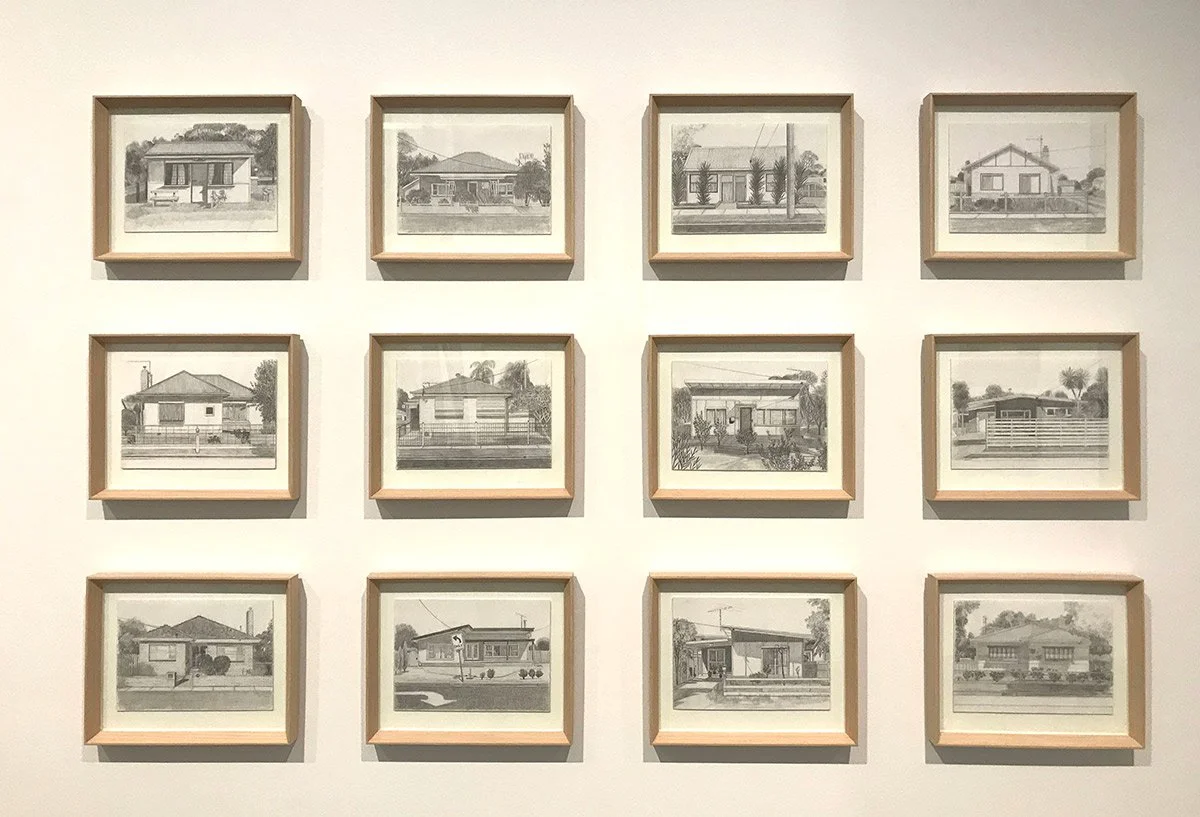 A display of twelve black-and-white architectural sketches of houses arranged in a 3x4 grid on a white wall.