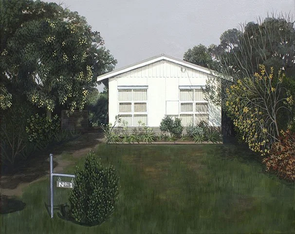 A white house with large windows, surrounded by trees and shrubs, with a lawn and a signpost in the front yard.