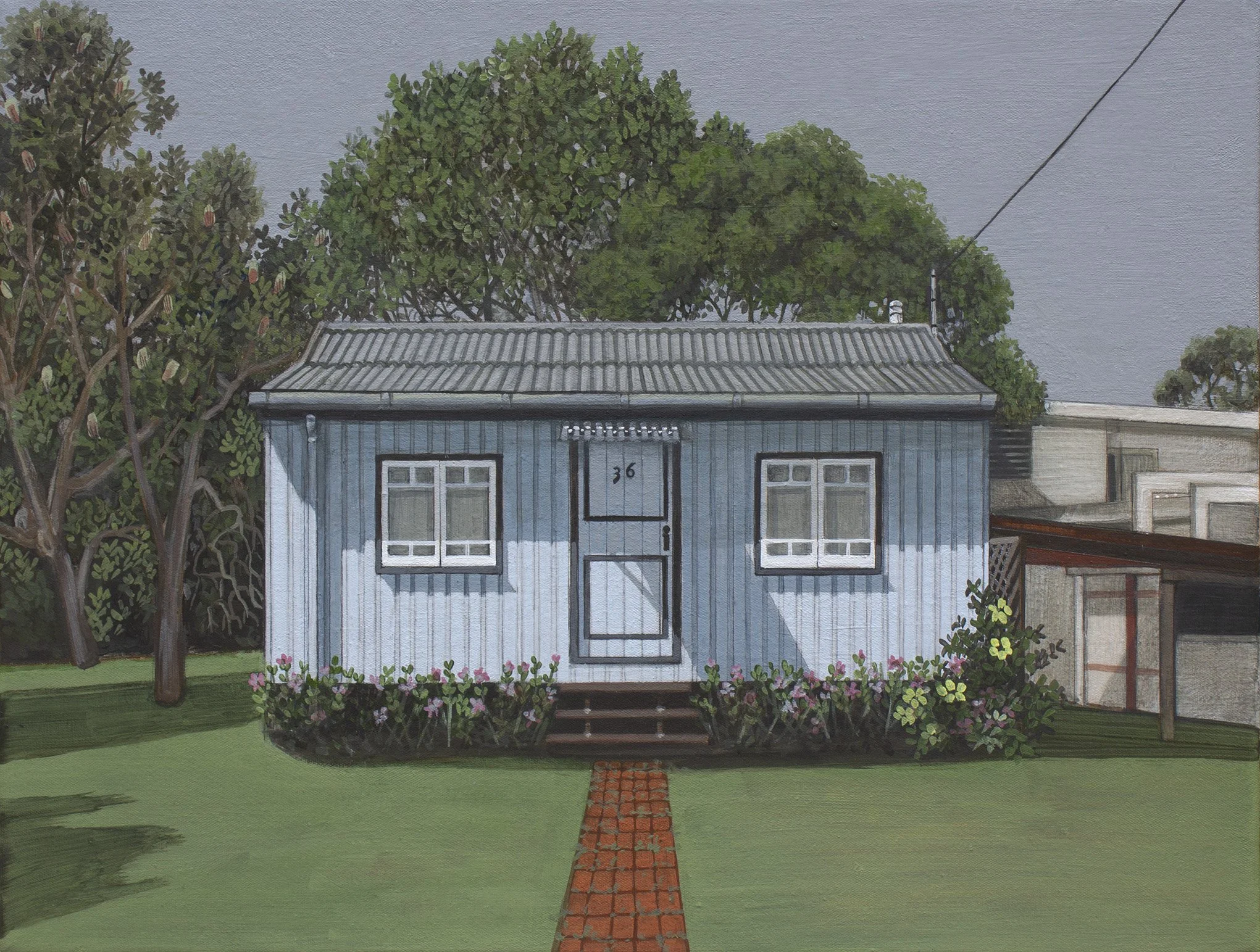 A house with a blue exterior, white-framed windows, and a gray roof, surrounded by trees and garden with pink flowers and a brick pathway in the foreground.