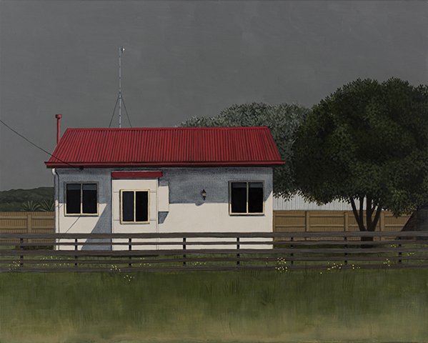 A house with a gray exterior, red roof, three windows, and a wooden fence in front, with trees and a cloudy sky in the background.