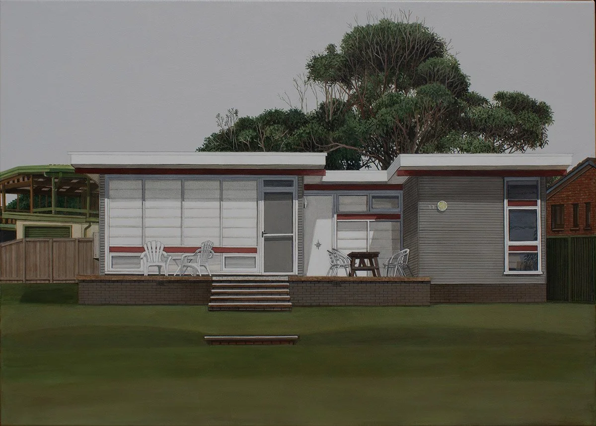 A modern house with large windows, a small front porch with outdoor chairs, and a green lawn with steps leading up to the porch. There is a large tree behind the house.
