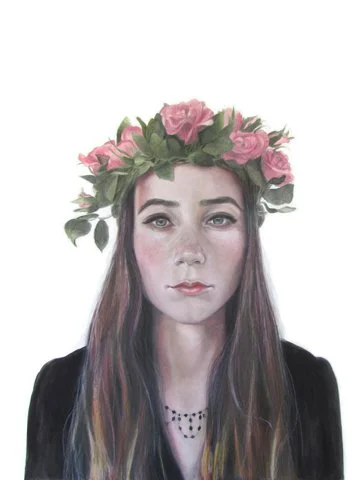 Portrait of a young woman with long brown hair wearing a crown of pink roses and green leaves, dressed in black with a necklace, against a white background.