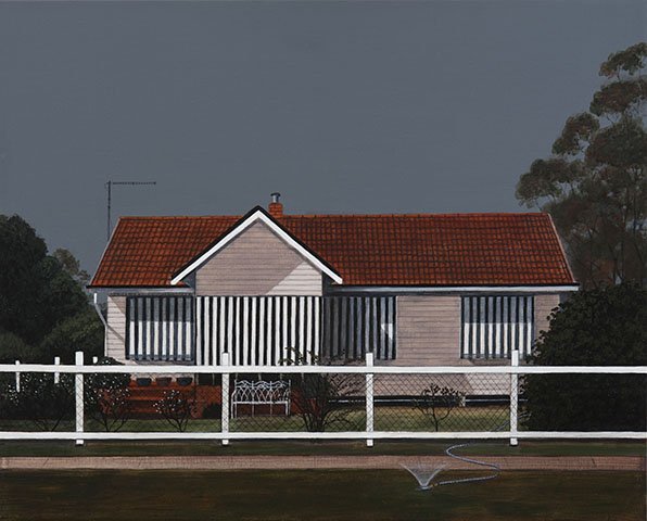 A house with a red tile roof, striped awnings on windows, a white fence in front, and a garden with bushes and a sprinkler.