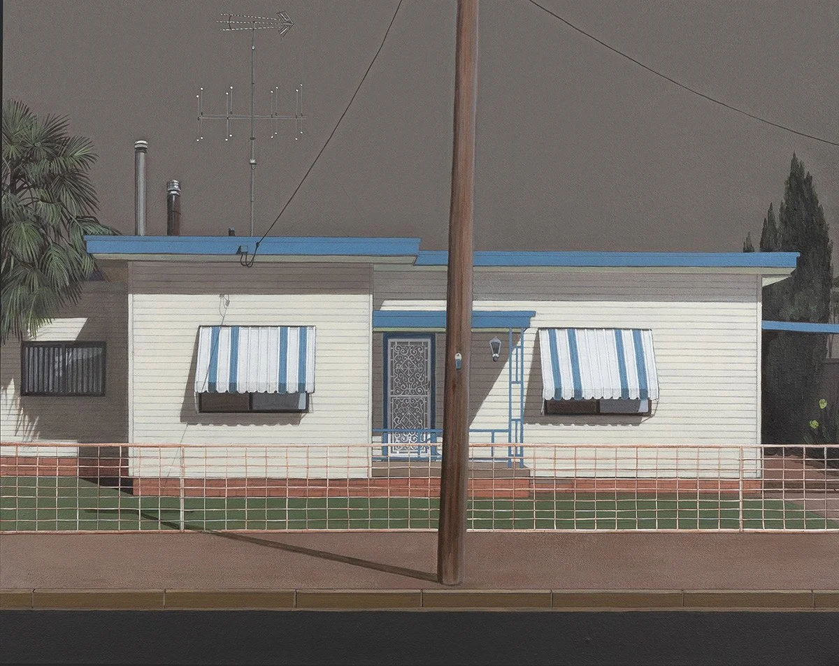A single-story house with white siding, blue roof, and window awnings with blue and white stripes. There is a front porch with a decorative metal security door, surround by a small lawn and a low pink fence. A large wooden utility pole blocks part of