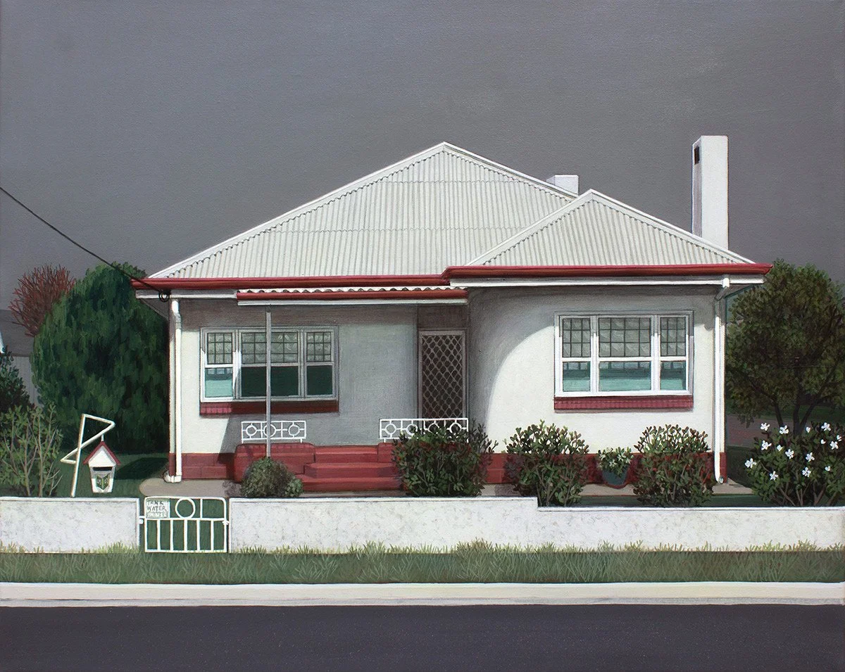 A house painted white with red trim and a corrugated metal roof, surrounded by bushes and a small white fence with a "No Water" sign.