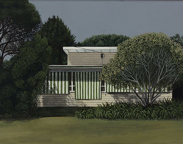 A house with a striped awning, trees, and bushes in the yard.