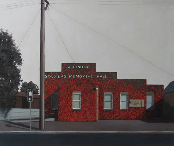 A building with a red and black poppy flower facade, labeled 'Goorong Soldiers Memorial Hall,' with a street sign and utility pole nearby.