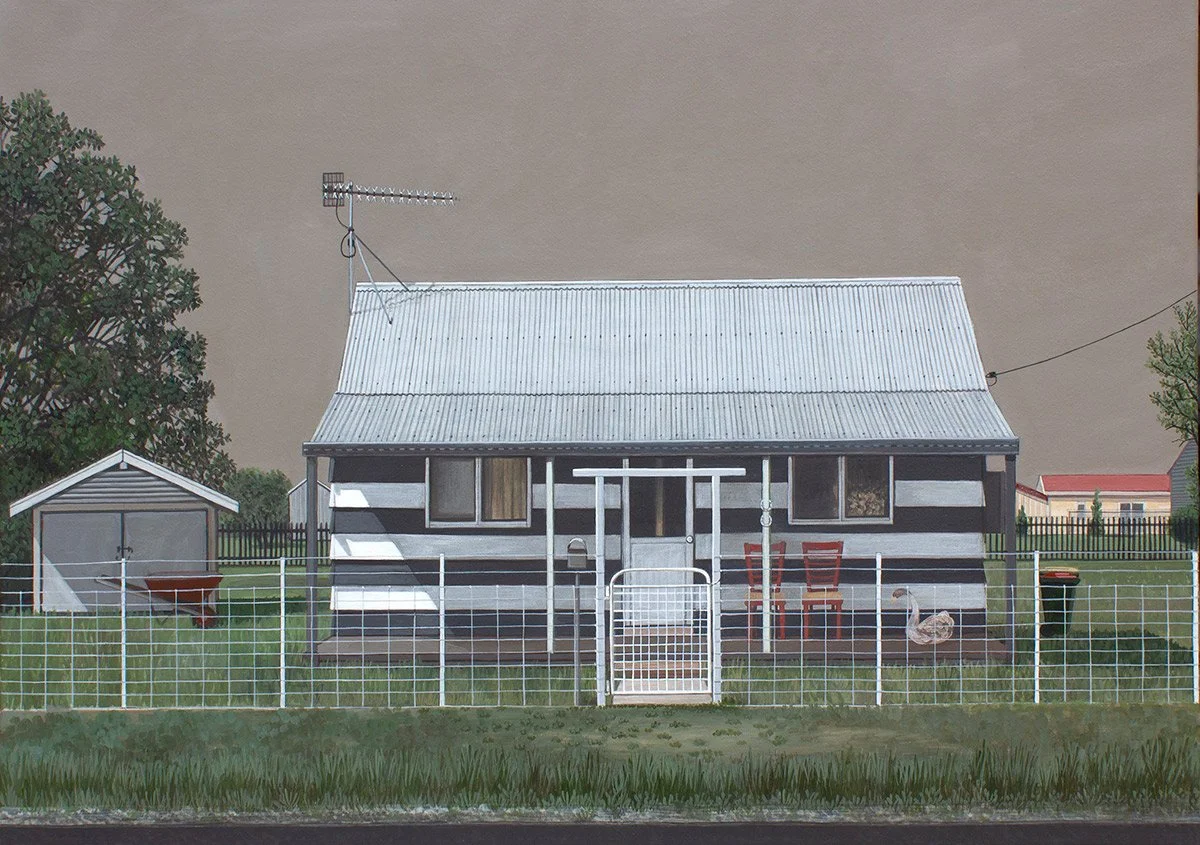 Front view of a small striped house with a metal roof, enclosed by a white fence, with outdoor furniture, a chicken, a small shed, and a grassy yard.