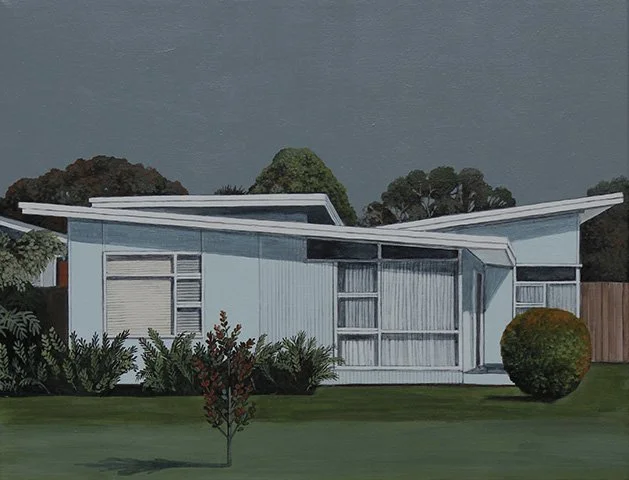A mid-century modern house with a unique angular roof, large windows, and a neatly mowed lawn with bushes and small trees in front.