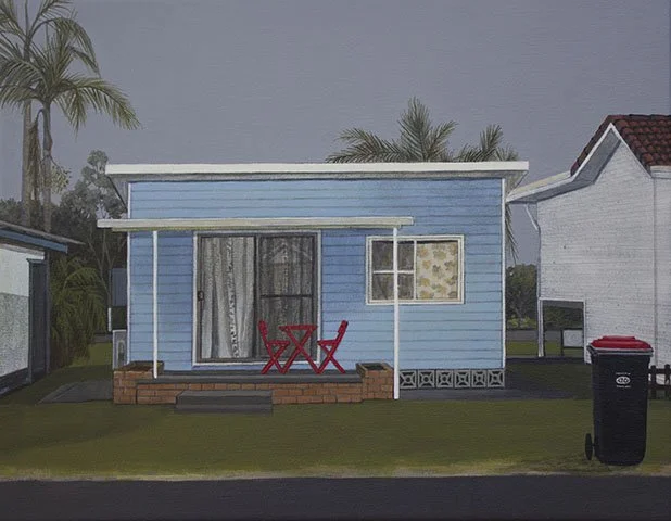 A small blue house with a brick porch, red outdoor furniture, a sliding glass door, and a window with floral curtains, surrounded by palm trees and neighboring houses.