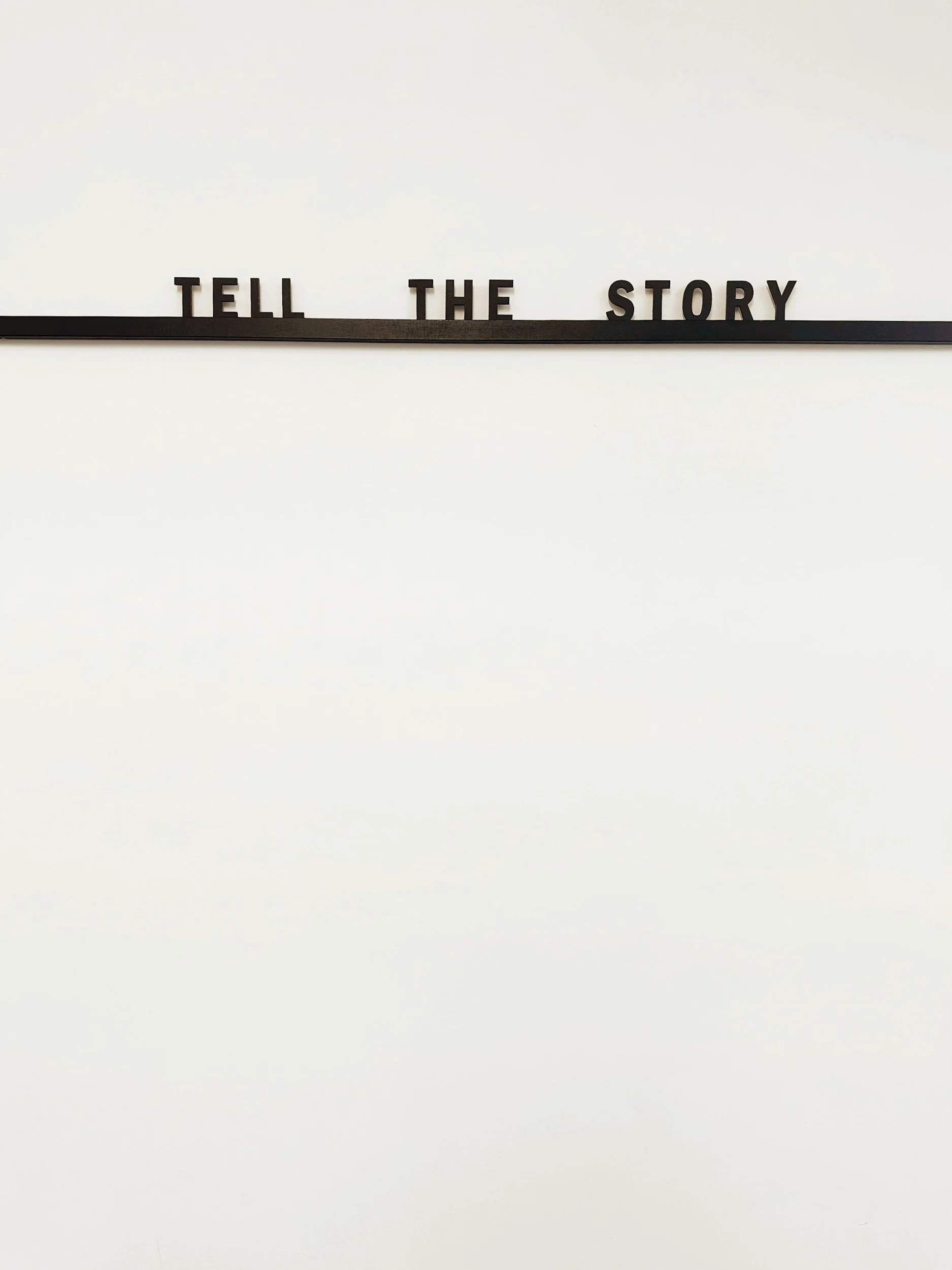 Wandschriftzug „Tell the Story" in Schwarz-Weiß als Symbol für Storytelling und narrative Texte