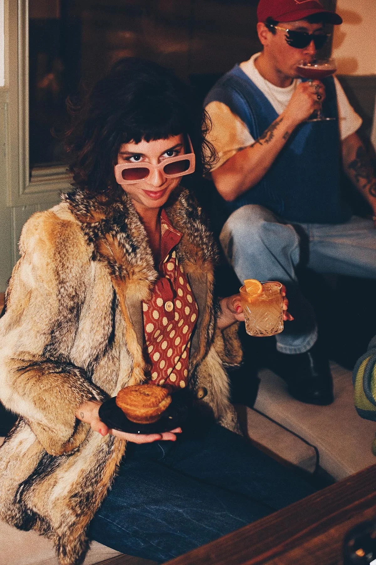 polaroid une femme vêtue d'un manteau de fourrure de style vintage, un cocktail à la main