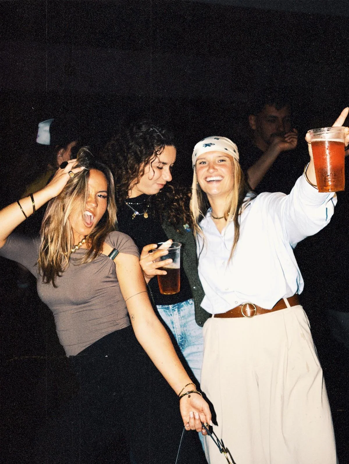 Groupe de jeunes femmes souriantes en fête, tenant des verres, dans une ambiance joyeuse.