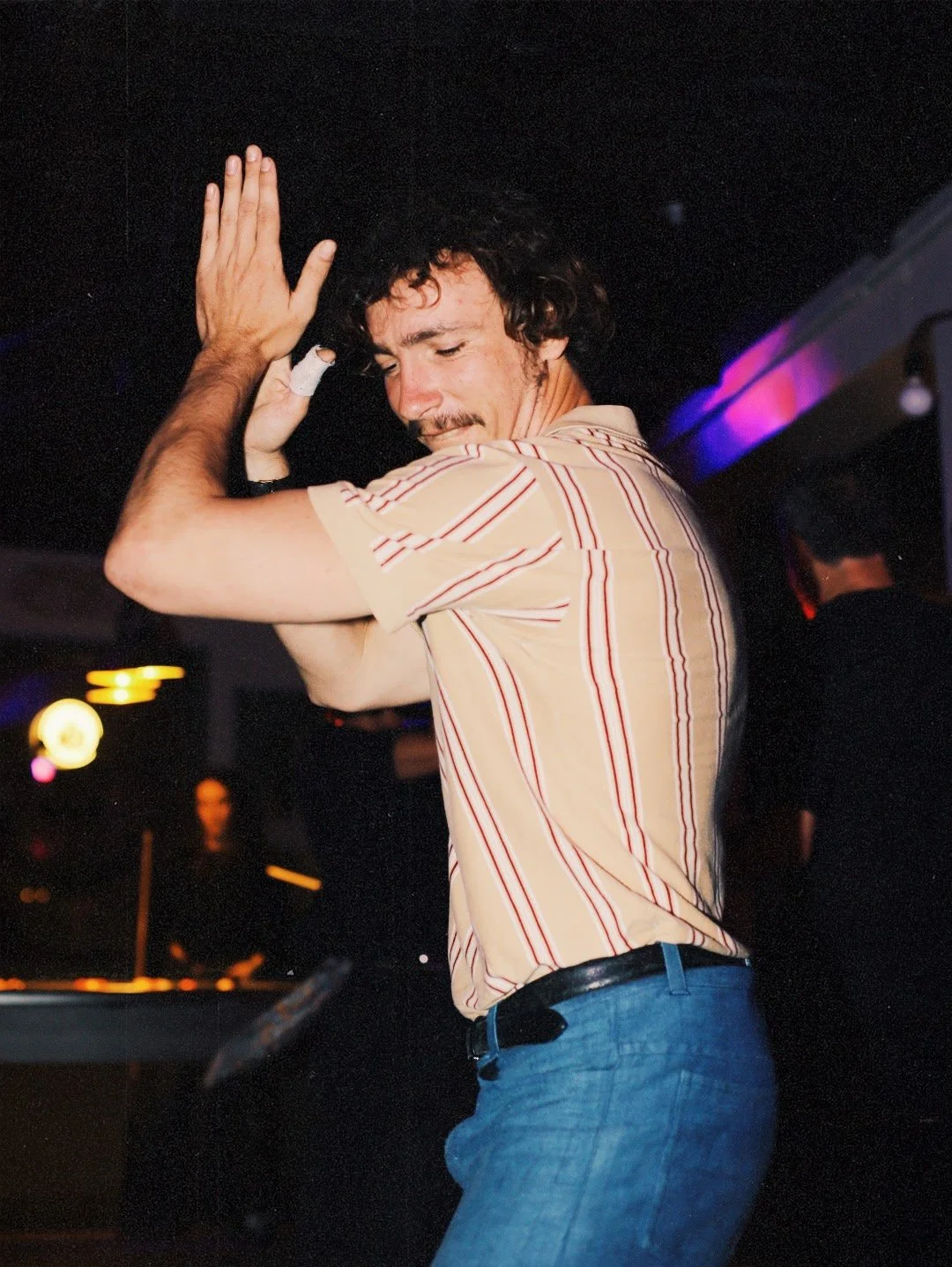 Un homme danse dans une boîte de nuit, avec un éclairage coloré en arrière-plan.
