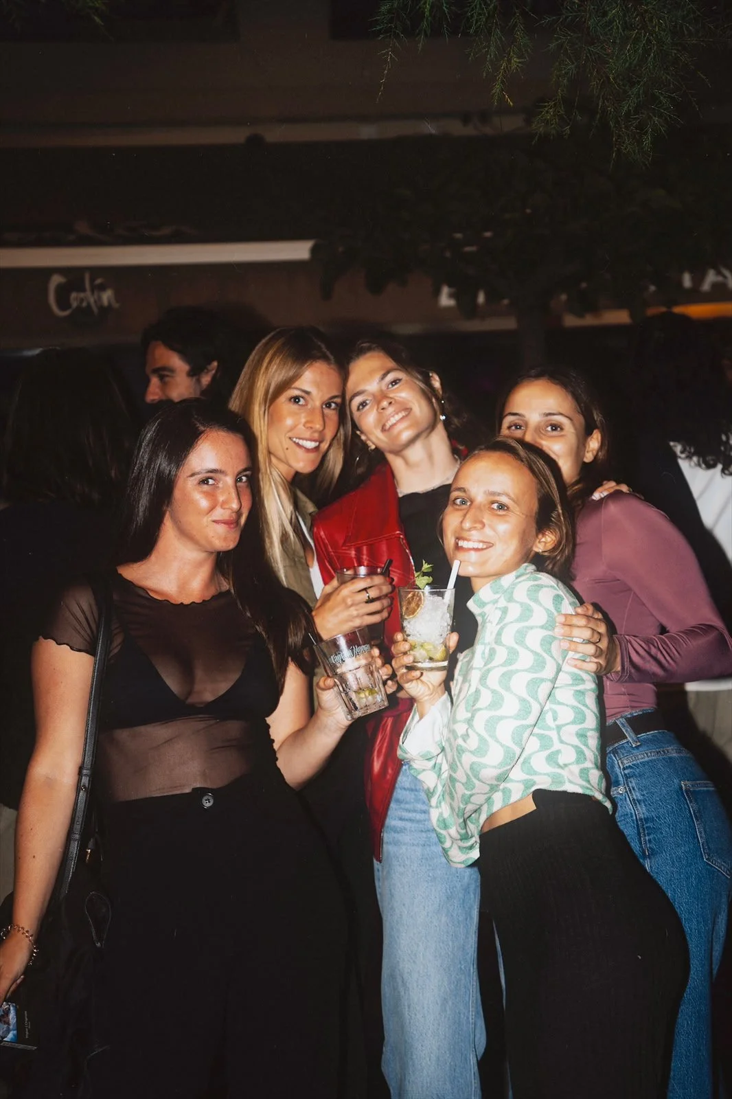 Groupe de femmes souriantes tenant des boissons dans un cadre de soirée