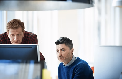 To mænd arbejder ved computerskærme i et kontormiljø