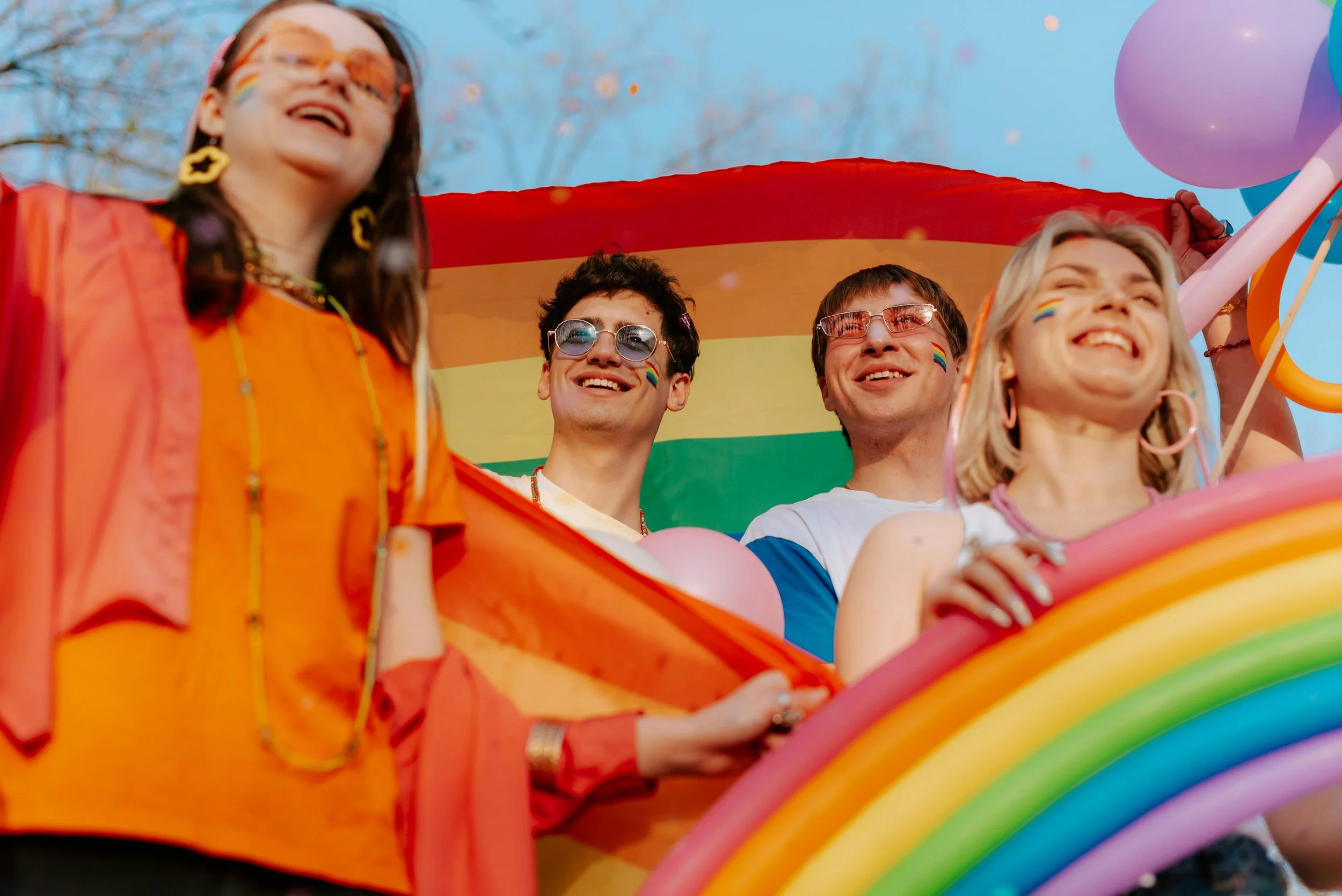 A joyful, vibrant queer celebration — warm colours, community, movement
