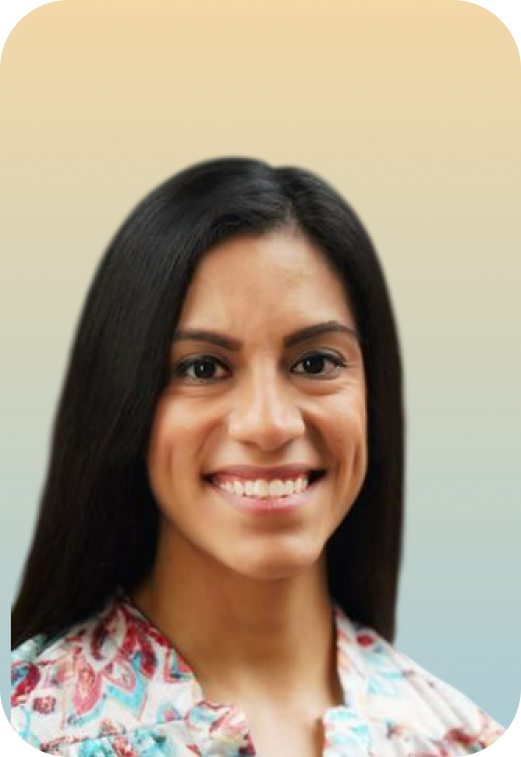 A woman with long dark hair and a braid, smiling, wearing a colorful patterned top, against a plain light background.