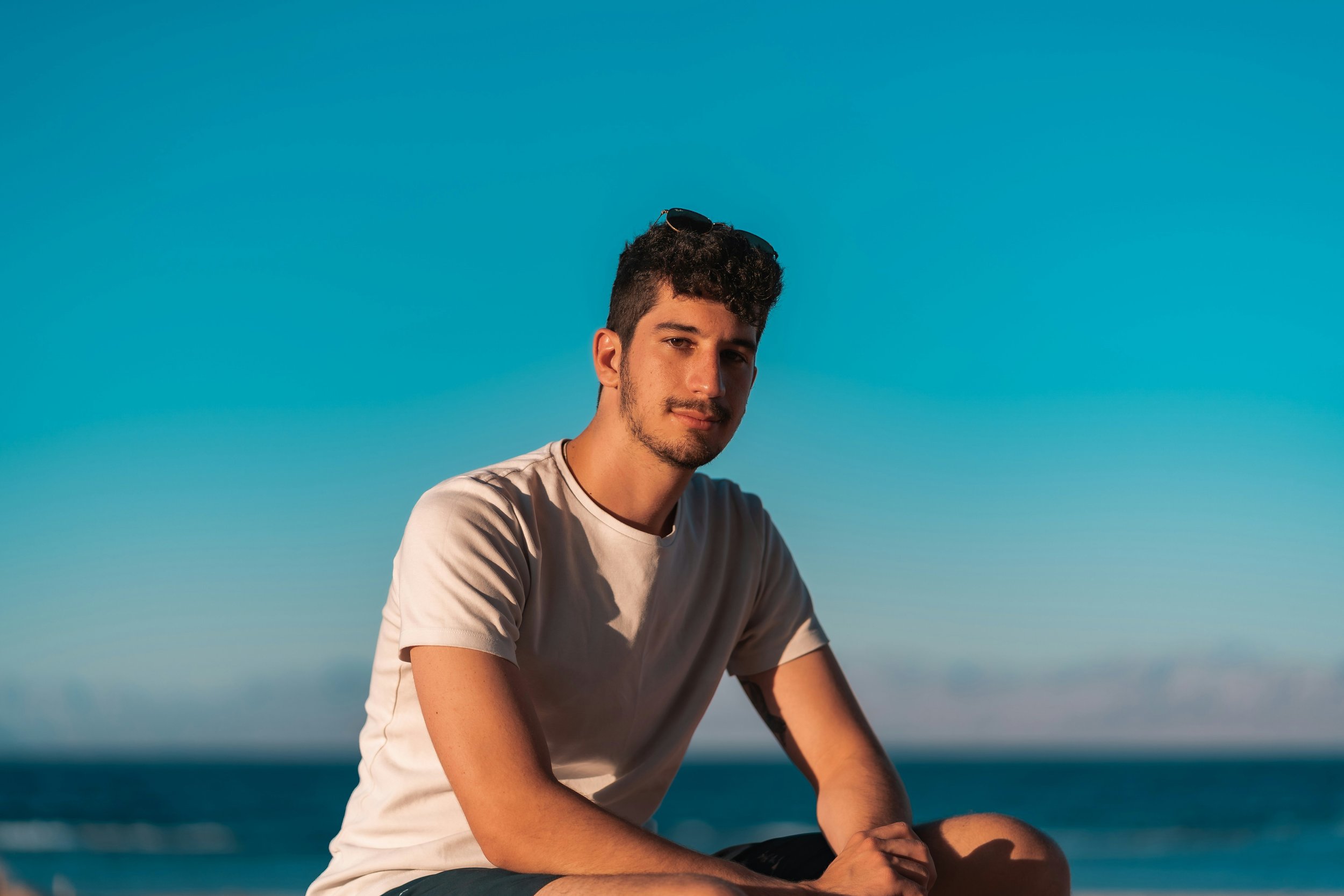 LGBTQ individual sitting under blue sky