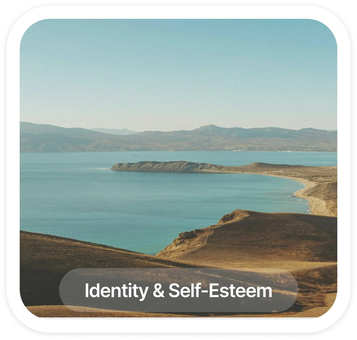 Scenic coastal landscape with rolling hills, a sandy shoreline, and water extending into the distance, under a clear sky. Text overlay says 'Identity & Self-Esteem'.