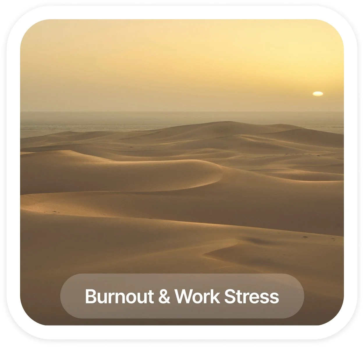 Sand dunes in a desert at sunset with a hazy sky.