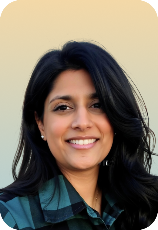 Close-up portrait of a woman with dark, wavy hair smiling and wearing a teal and black plaid shirt against a light gradient background.
