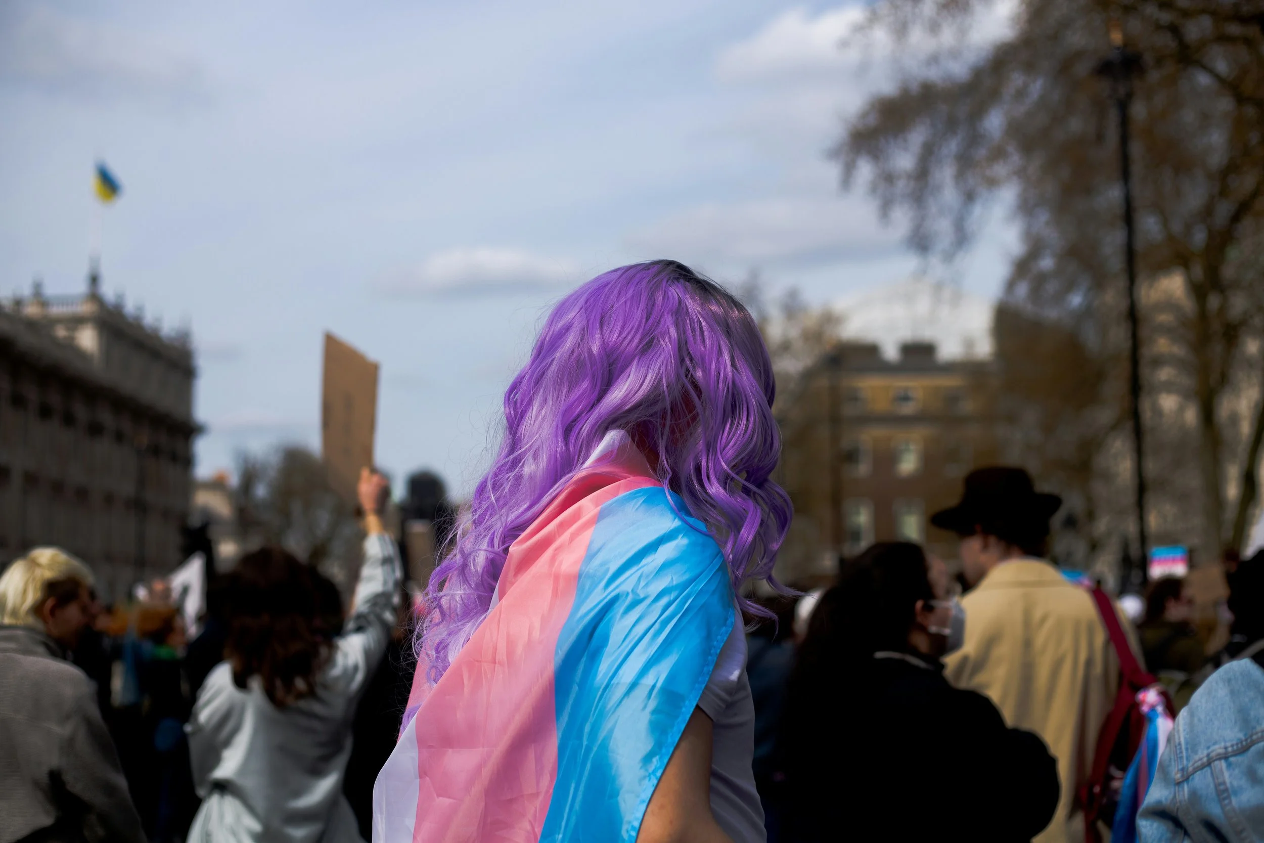 woman with purple hair wearing a trans flag