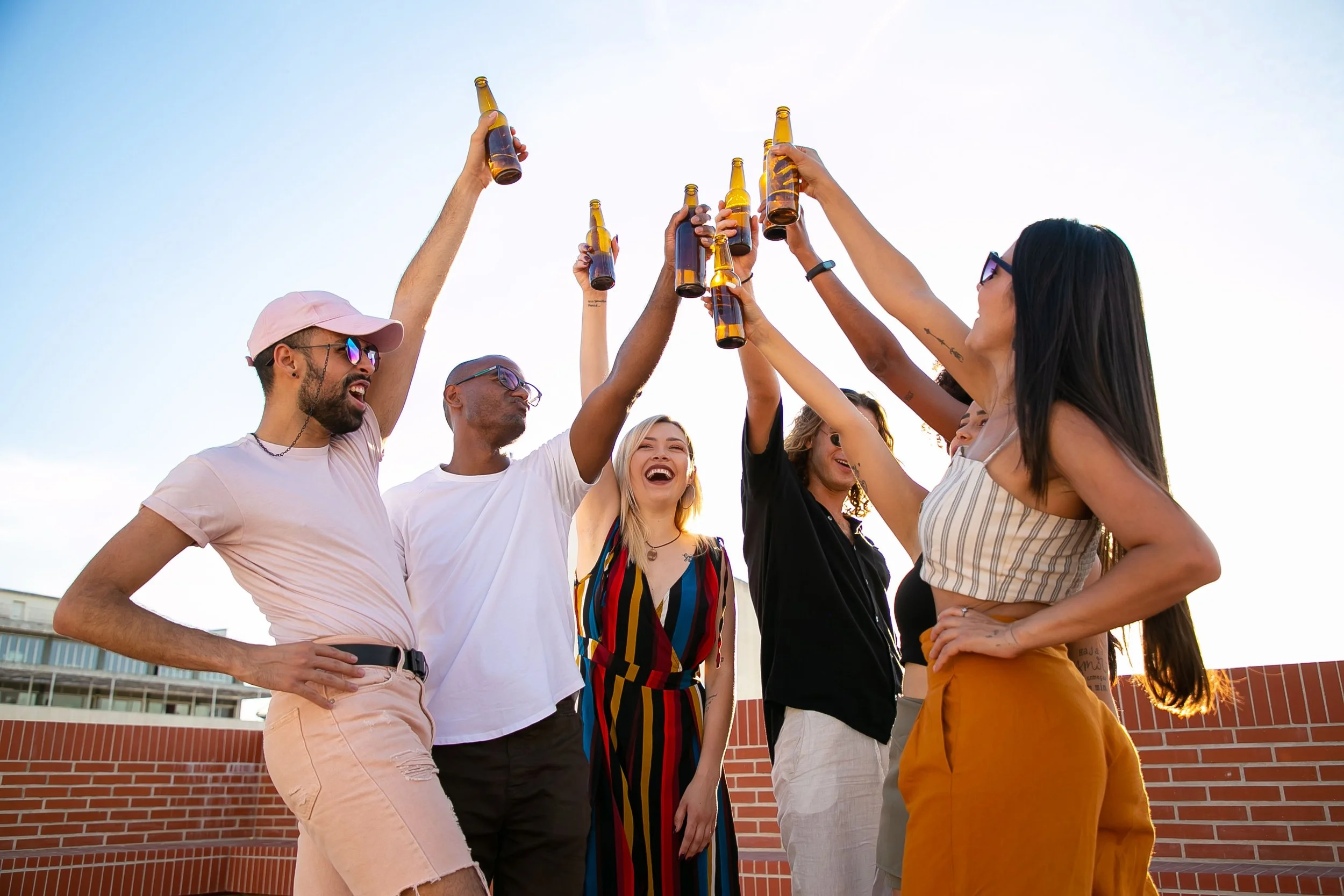 Group of diverse friends enjoying drinks and laughter on a sunny rooftop