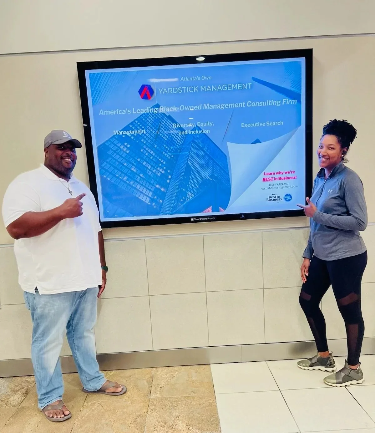 Ayana Parsons with her husband Ebbie Parsons pointing to a sign that says Yardstick Management