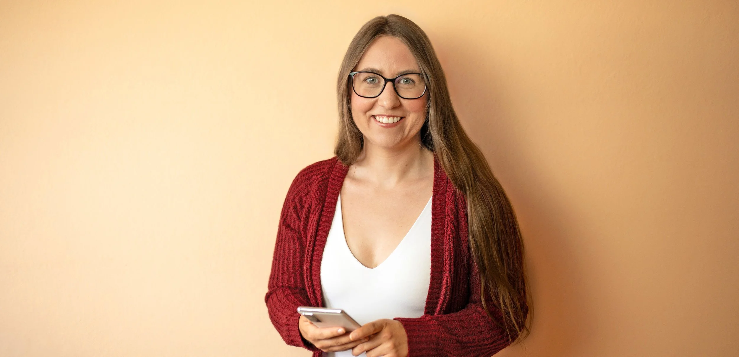 Performance Marketing Managerin Eva Rieger lächelnd mit Smartphone in den Händen