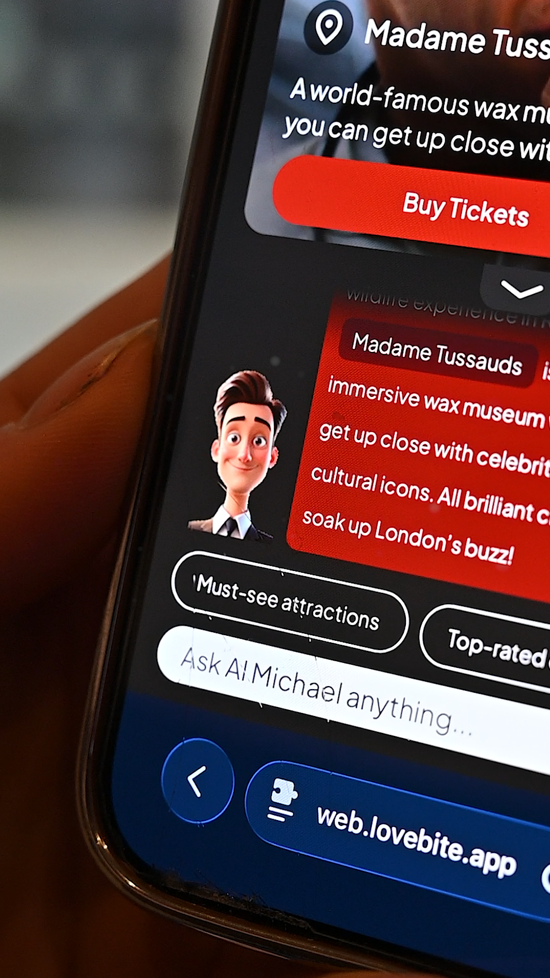 Close-up of a smartphone showing a Madame Tussauds V-Guide experience with AI Michael.