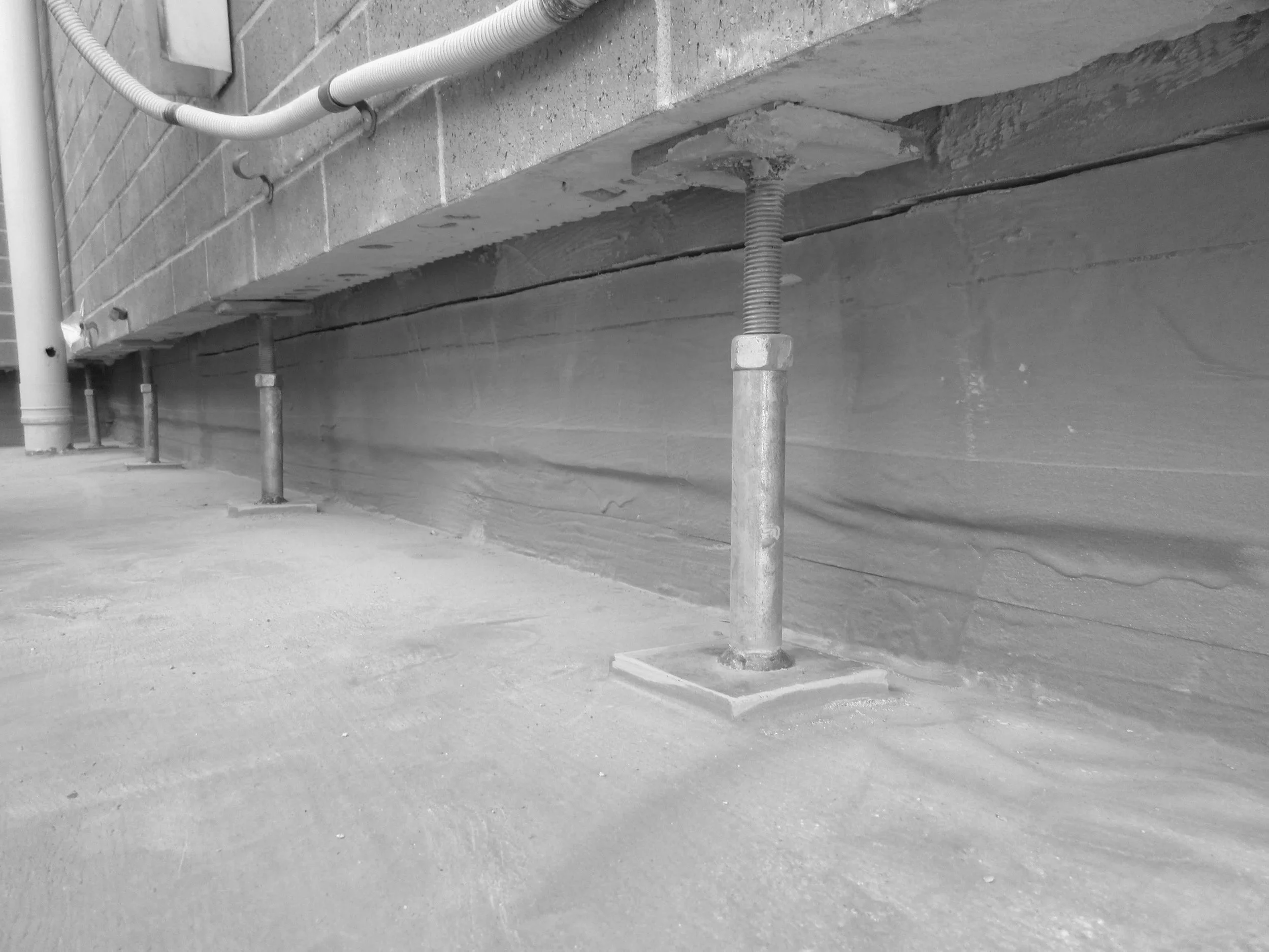 A concrete foundation with metal support pipes and electrical conduits at a construction site.