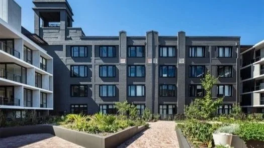 Modern multi-story residential building with landscaped garden in foreground