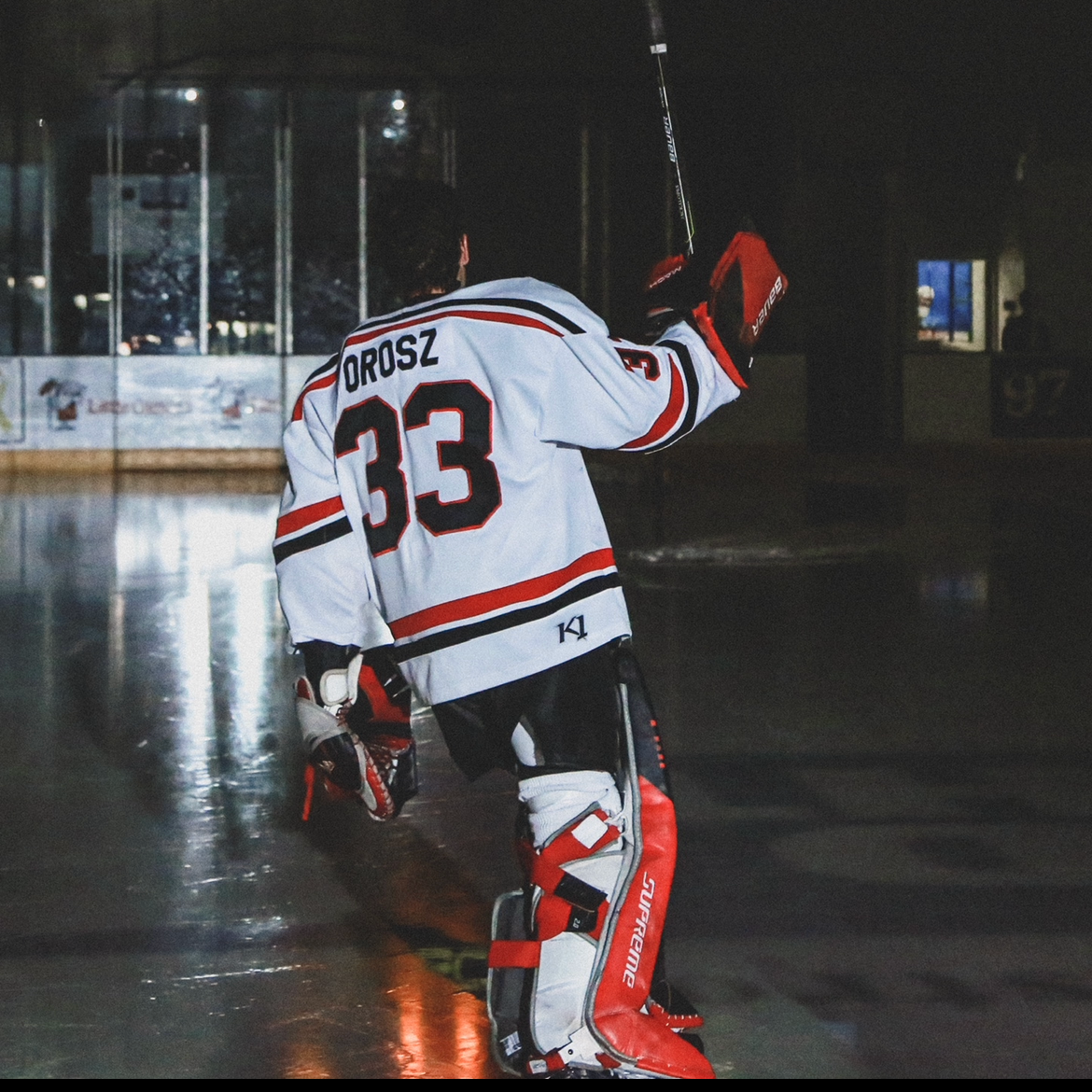 Ice hockey player with jersey number 33 and name DROSZ, wearing red and white goalie gear, walking on an ice rink.