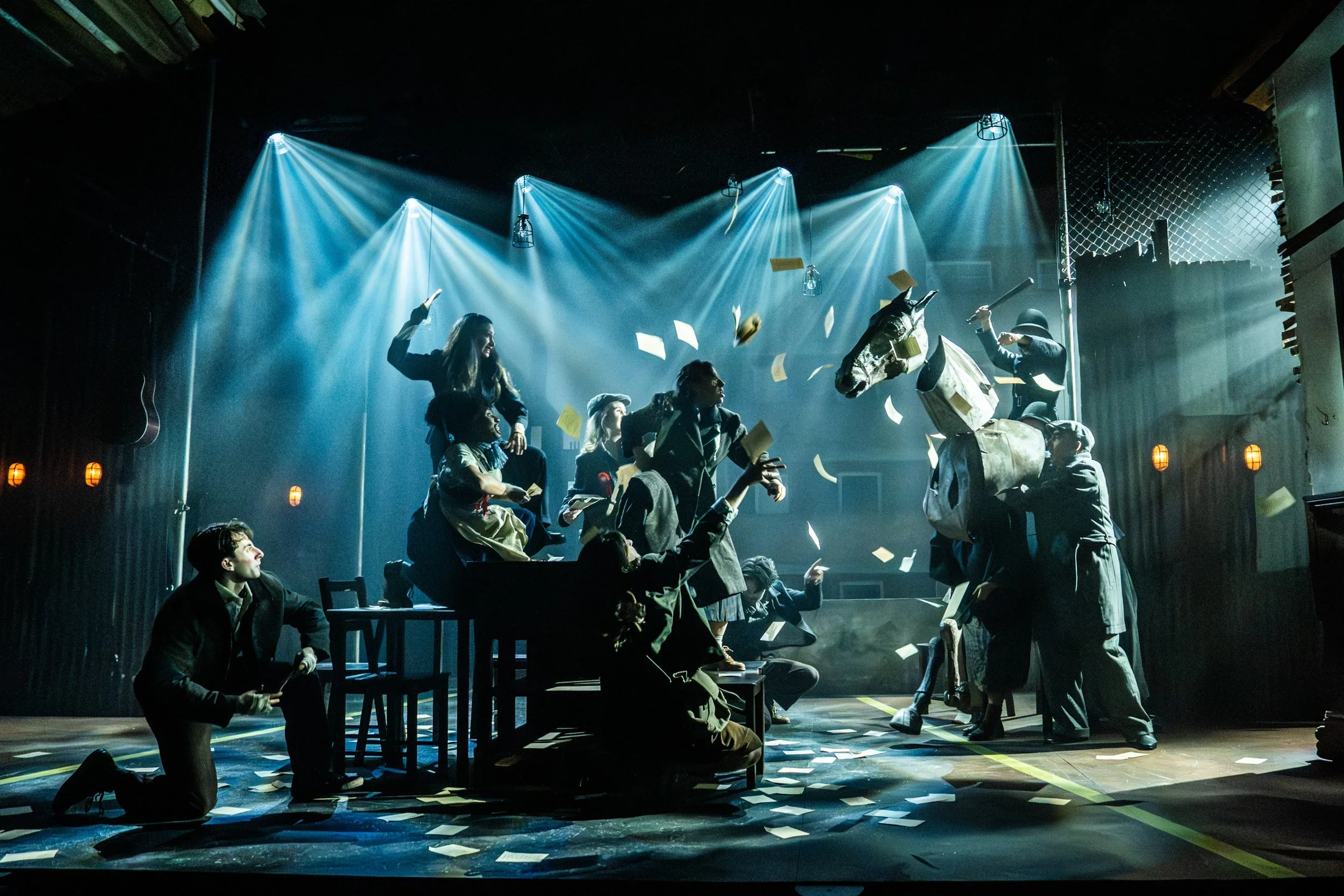 "Cable Street" production shot: full company in the climactic moment of "The Battle" including the large puppetry horse in silhouette. Photo by Johan Persson.