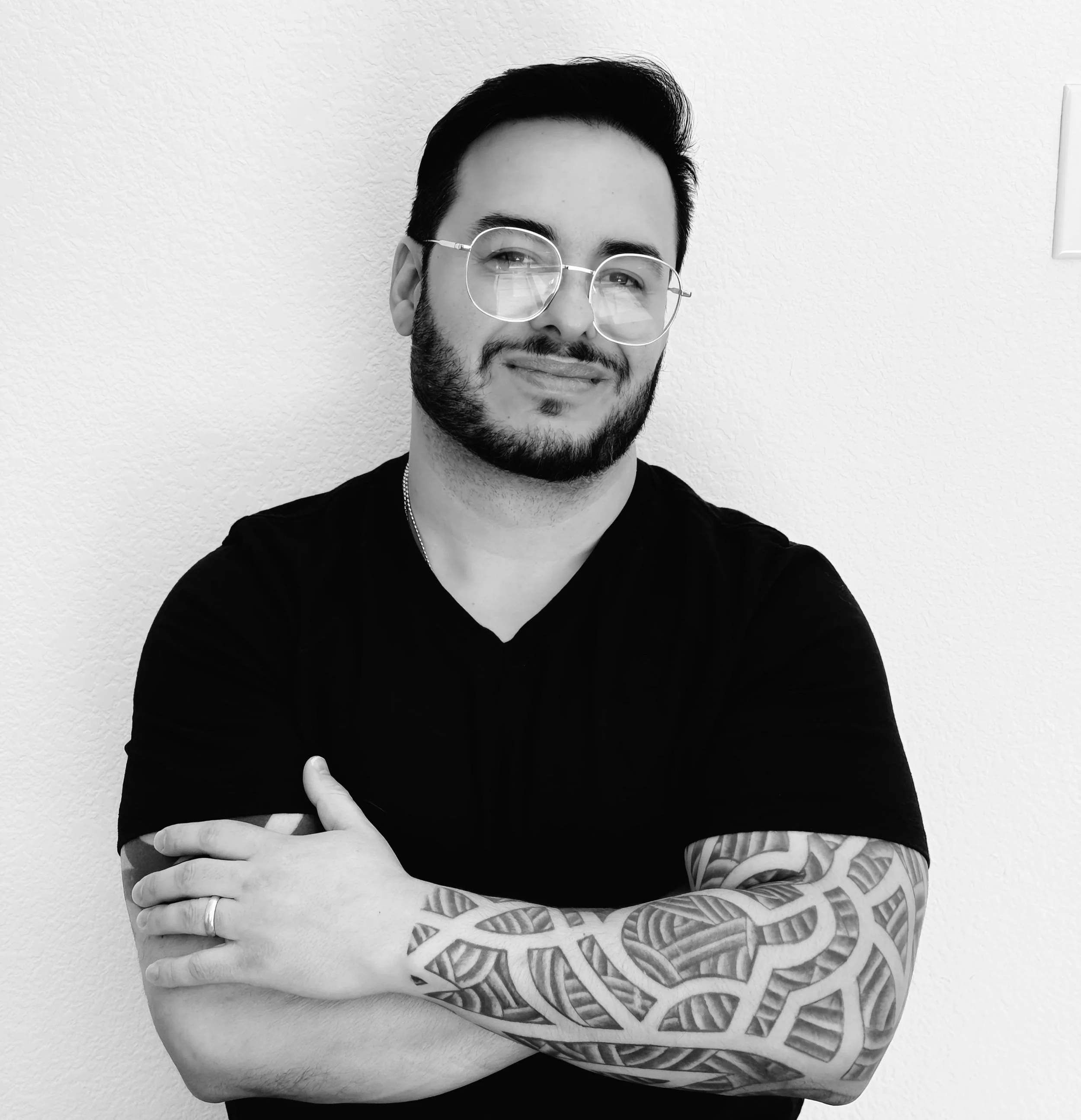 Professional headshot of an expert accent reduction and clear speech coach with glasses, smiling confidently with arms crossed.