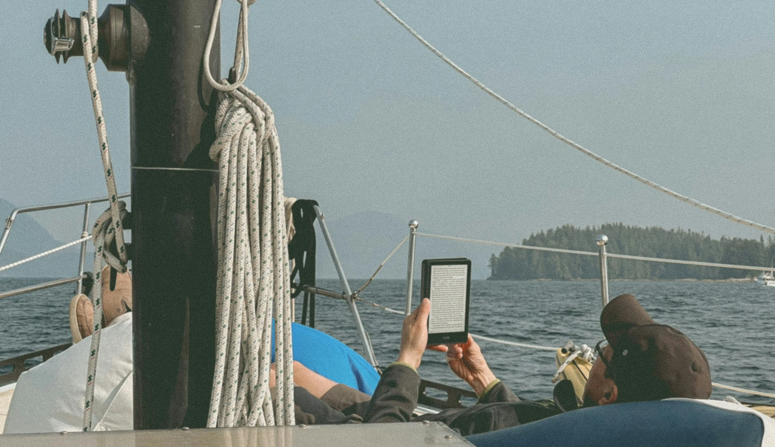 View of a boat sailing on the water with a scenic island in the background, viewed from the deck.