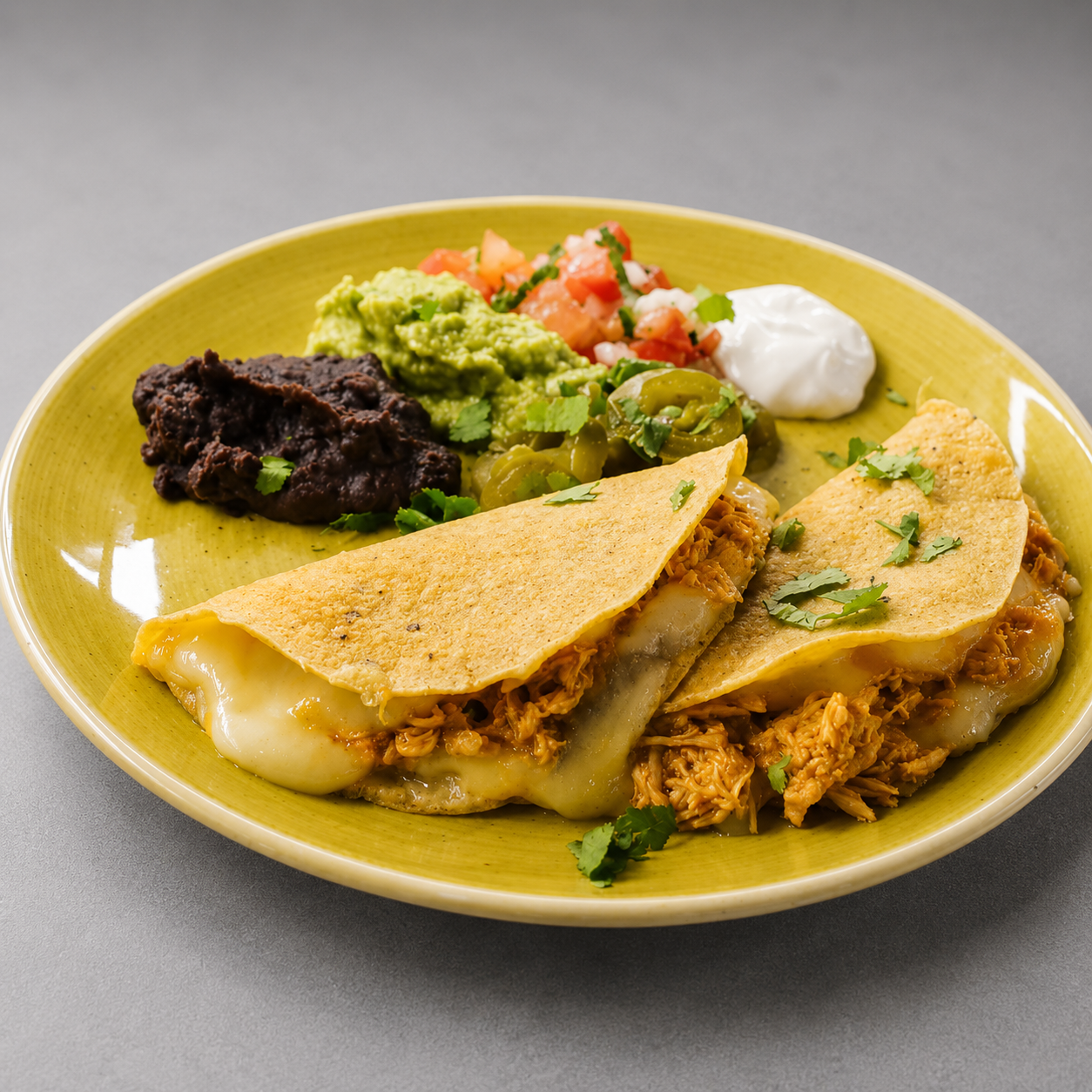Plato de tacos con pollo desmenuzado, tortillas, guacamole, pico de gallo, salsa, crema y frijoles refritos.